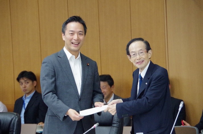意見書を手交する平松会長(右)と村井政務官(左)